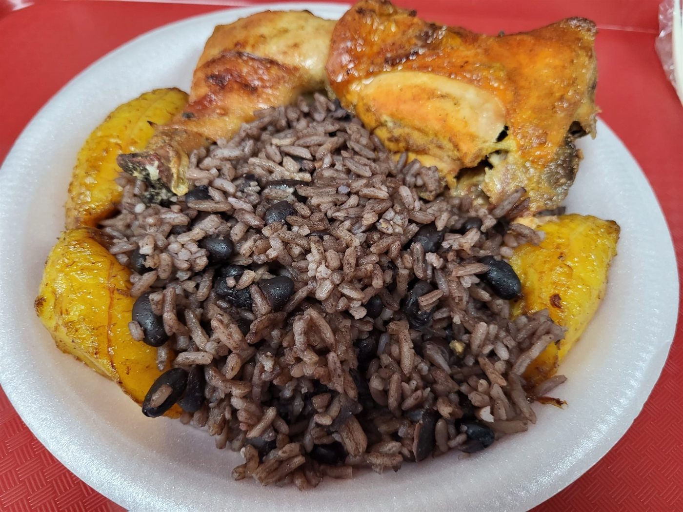 Plato de pollo horneado con arroz moro de habichuelas negras y amarillos fritos de Cafetería Jardín Criollo