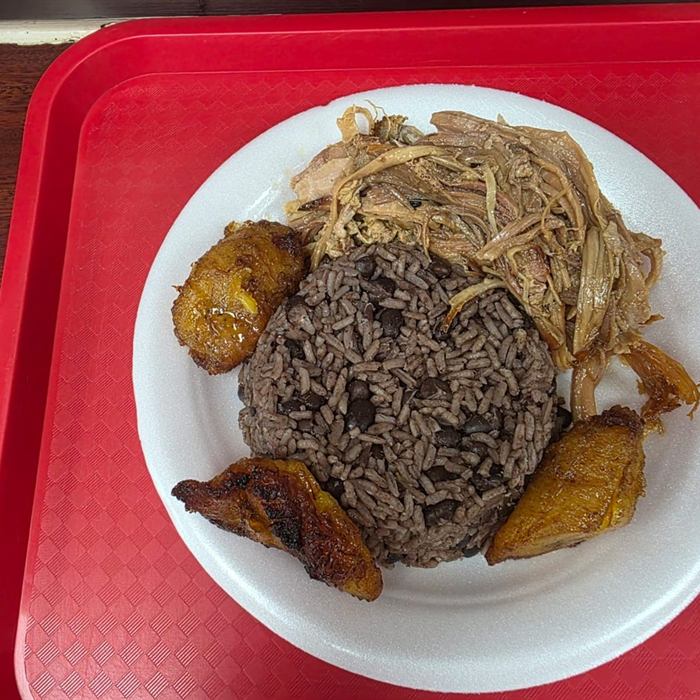 Arroz moro con habichuelas negras rodeado de amarillos caramelizados y pernil dorado