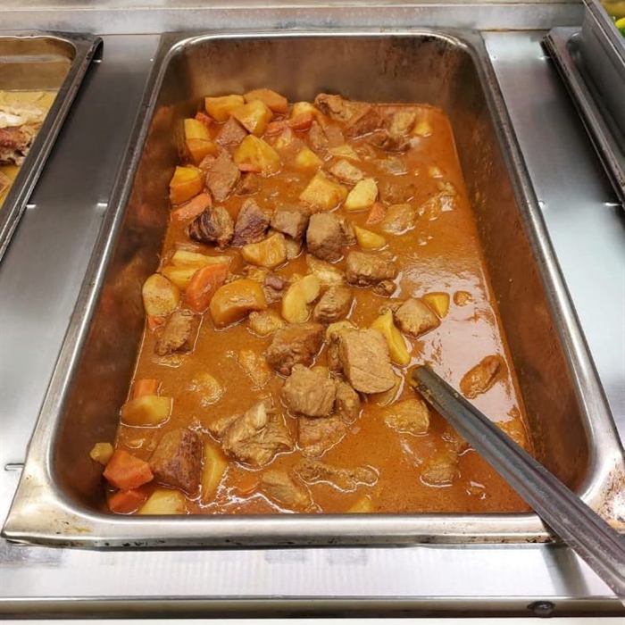 Bandeja de servicio llena de carne guisada con papas y zanahorias en salsa espesa