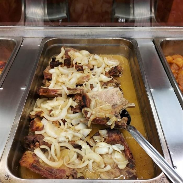 Bandeja de servicio con chuletas de cerdo guisadas en salsa dorada cubiertas de cebolla en tiras