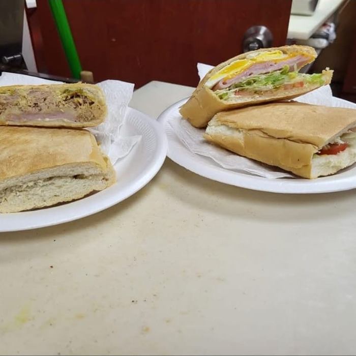 Dos platos con un sándwich prensado cada uno, cortados a la mitad mostrando el relleno