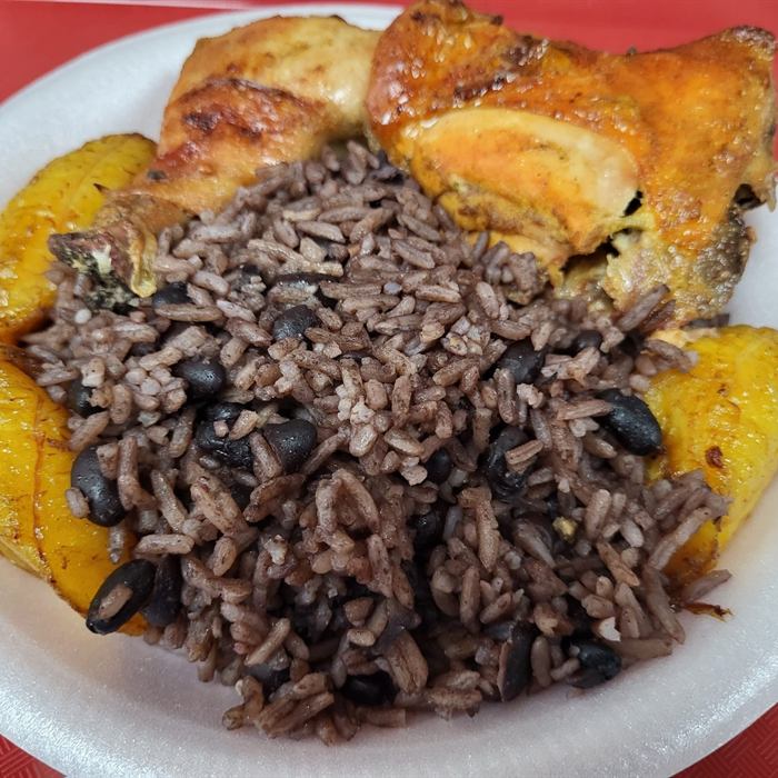 Plato de foam con presas de pollo horneado, arroz moro con habichuelas negras y tajadas de amarillos fritos